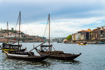 Fototapeta na wymiar Typical portuguese boats transporting wine barrels on the river Douro in Porto