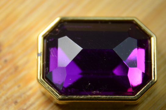Isolated purple diamond with gold details on wooden background