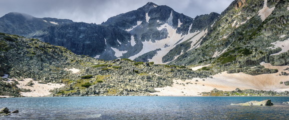 Panorama of Rila mountain lake and Musala summit on a misty, snow covered landscape