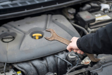 Professional auto mechanic holding wrench is maintenance the engine car. Auto repair garage