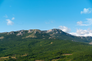 blue sky with clouds over green mountains