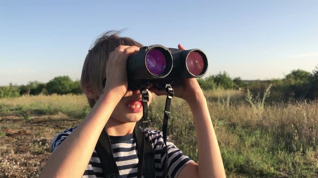 boy looking through binoculars in nature