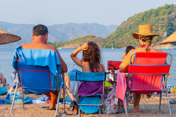 Three people resting on the beach. Family tourism concept