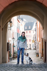 young man with a dog in the city. walk with a pet. Charming guy and Australian Shepherd