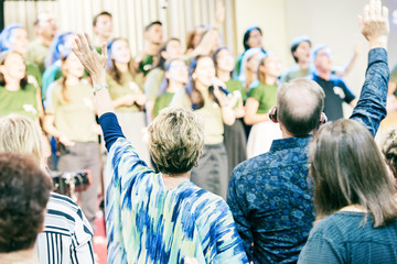 People at church, worshiping God, with hands up.
