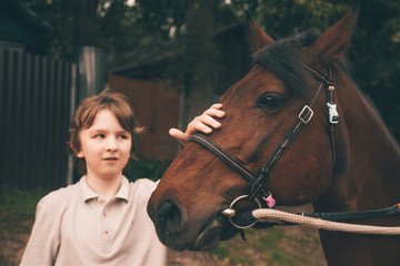 Fototapeta premium little child boy and his friend brown horse