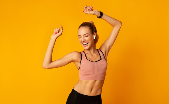 Excited Young Lady In Sportswear Dancing On Yellow Background
