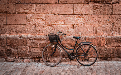 Fototapeta na wymiar Black vintage bicycle parked against an old stone wall in Ciutadella, Minorca island in Spain.
