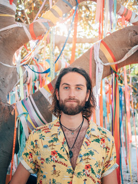 Pensive handsome bearded hipster man standing under decorated tree looking at camera