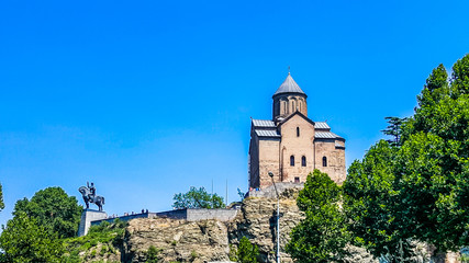 Fototapeta na wymiar Metekhi Church of Assumption and Vakhtang Gorgasali monumen on the top of the rock on the bank of river Kura. Tbilisi, Georgia