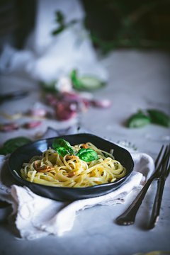 From above appetizing pasta with vegetables basil in black bowl on served table