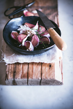 From above ripe garlic ready for ready for cleaning with knife in black bowl on wooden stand