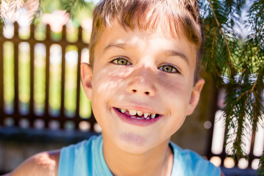 Portrait of little boy in blue t-shirt with green eyes and croocked teeth.