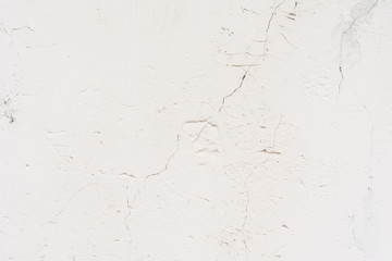 texture of an old wall with uneven cracked stucco, white surface of the exterior painted wall, abstract background