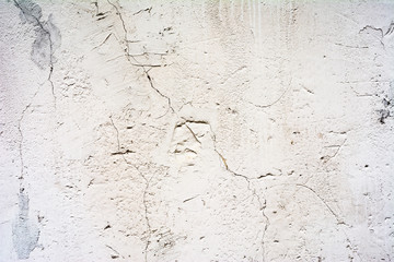 texture of an old wall with uneven cracked stucco, white surface of the exterior painted wall, abstract background