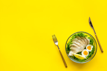 salad in bowl and flatware on yellow background top view space for text