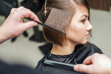 Professional hairdresser combing with a comb short hair. Hair salon. Woman haircut. Cutting
