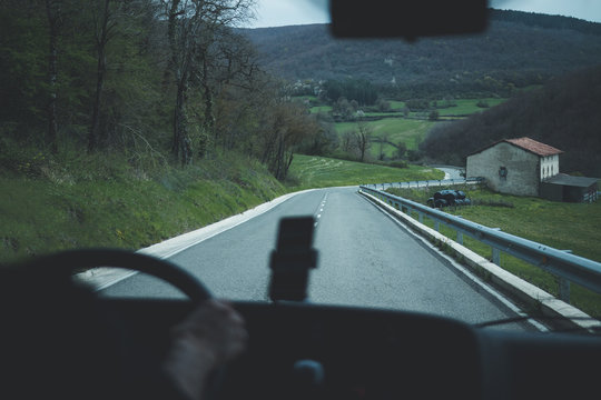 View from inside car of empty road of rural area in overcast weather