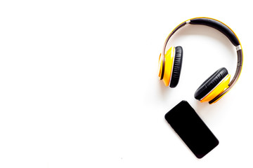 Naklejka premium Wireless headphones and mobile phone as music gadgets on white background top view copyspace