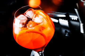 Aperol spritz cocktail in big wine glass with orange and ice, summer alcoholic cold drink, dark bar...