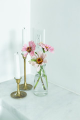 pink daisies flower in glass vase and candlesticks on marble bathroom counter, bathroom decor