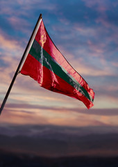 Transnistria flag, Pridnestrovian Moldavian Republic flag waving on sky at dusk	