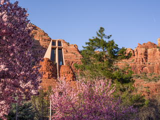 Sedona in spring - Chapel of the Holy Cross surrounded by red rocks, green trees and blossoming trees in foreground