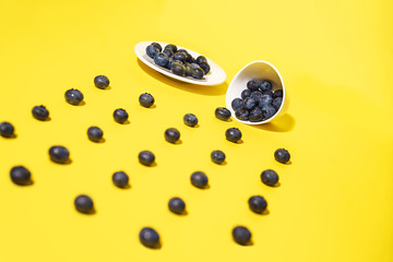 Fresh blueberry and white dishes on yellow background.