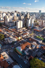 Fototapeta na wymiar Aerial view of streets and avenues in Pinheiros neighborhood with commercial buildings and small houses at dusk on sunny summer day. The neighborhood has old houses and modern office buildings.