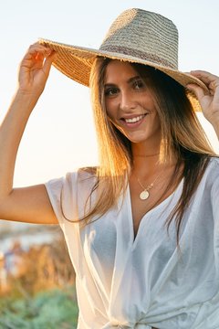 Young beautiful female model in white clothes smiling and looking at camera in nature