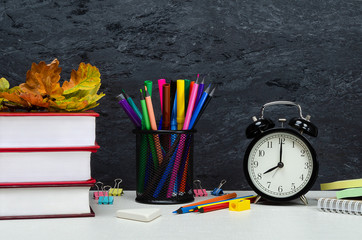 8 am Back-to-school. On the schoolboy&rsquo;s desktop is an alarm clock, books, pencils and autumn foliage are.