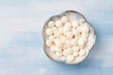 Hyaluronic Acid Tablets. Concept for a healthy dietary supplementation. Bright wooden background. Top view. Close up. Copy space.