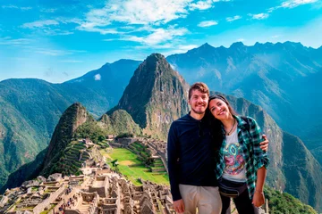 Papier Peint photo Machu Picchu Jeune couple de touristes à Machu Picchu. Ils sont ensemble, heureux et détendus. Derrière, la ville de Machu Picchu et la montagne Huayna Picchu. Site archéologique, patrimoine mondial de l& 39 UNESCO