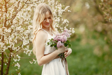 Beautiful girl in a white dress. Woman in a spring blooming park