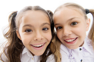 A whole new look. Happy school girls. Adorable little girls smiling isolated on white. Primary school girls with charming smiles and long ponytails. Cute girls classmates. making selfie