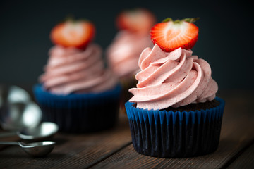 Chocolate cupcakes with strawberry meringue butter cream on a wooden table