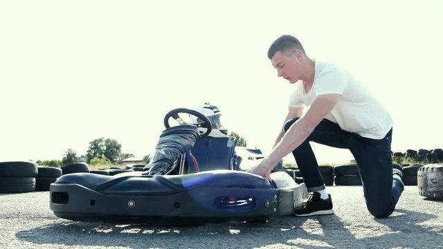 attractive man checking tire pressure on his gocart before starting his race