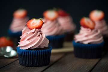 Chocolate cupcakes with strawberry meringue butter cream on a wooden table