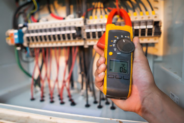Workers use clamp meter to measure the current of electrical wires produced from solar energy for...