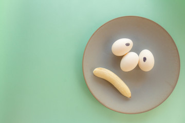 Funny face made with food. Eggs forming eyes. Mouths shaped like bananas. Food humanization. Free space to write. Conceptual image