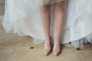 Fototapeta na wymiar Bride in a beautiful wedding dress putting on shoes.