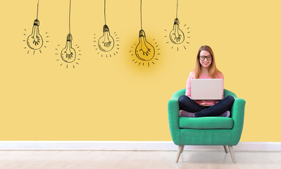 Idea light bulbs with young woman using her laptop in a chair