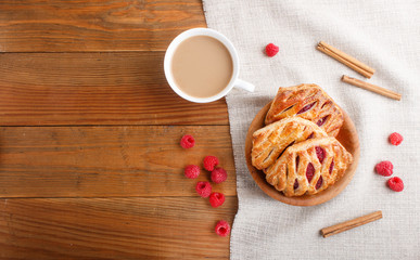 puff pastry buns with strawberry jam on wooden background with linen textile and a cup of coffee. top view.