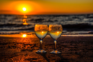 glass of champagne on the seashore at sunset background.