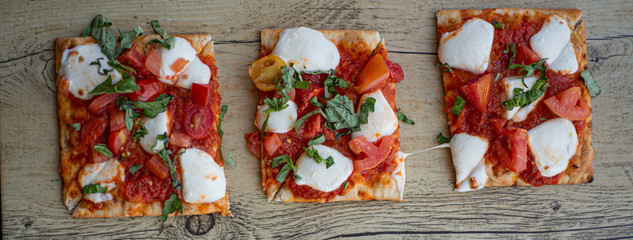 Three pieces of Classic Margherita Flatbread Pizza on wooden board. Wide photo and Above view.