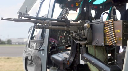 A rapid fire machine gun attached to the side of a military helicopter