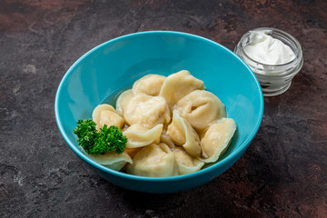 Dumplings with sour cream and herbs on dark concrete rustic table