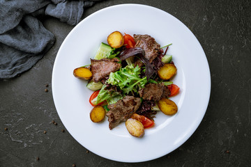 Steak salad with beef on black concrete table