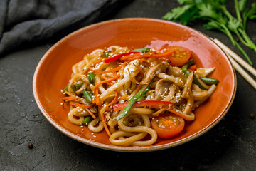 wok noodles with vegetables on black concrete table