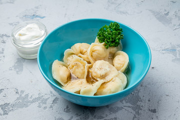 Dumplings with sour cream and herbs on grey concrete table